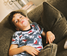 A young boy lying on a couch and watching TV