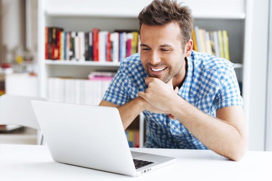 Happy man looking at his laptop