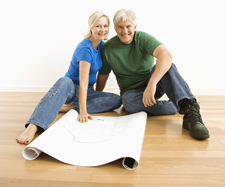 A happy elderly couple sitting together on the floor of an empty room