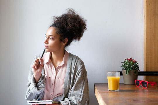 female is thinking while writing in her journal