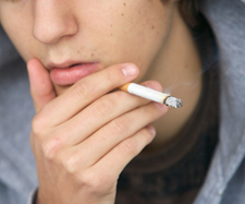 bottom half of a young teenage boy’s face smoking a cigarette